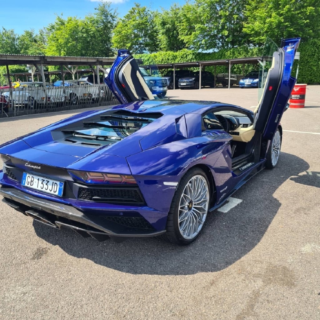 Blue Lamborghini Aventador with scissor doors raised in the paddock