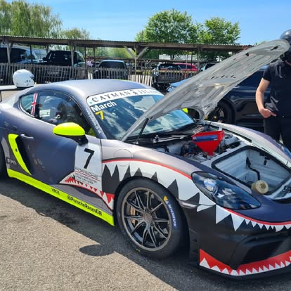 Porsche Cayman GT4 race car with shark livery — paddock preparation