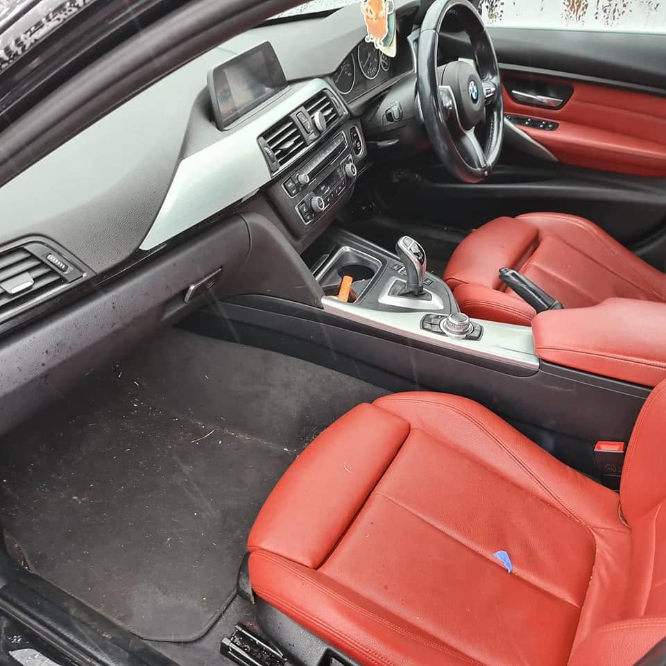 BMW M Sport red leather interior before — debris on carpet, cigarette in cupholder, dusty dash