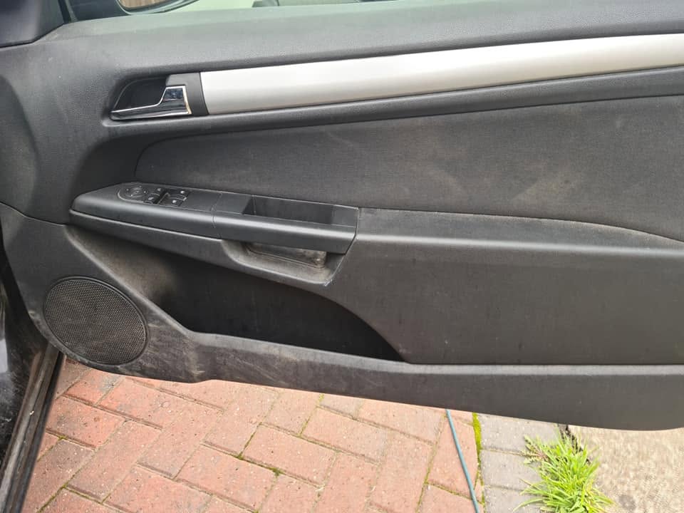 Door card before — heavy dust and grime on fabric panels, dirty speaker grille and pocket