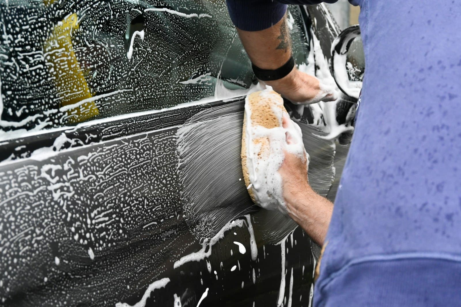 Careful two-bucket hand wash — thick suds worked over black paintwork